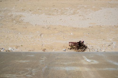 Free A coastal scene showing sand and scattered debris against a concrete foreground. Stock Photo