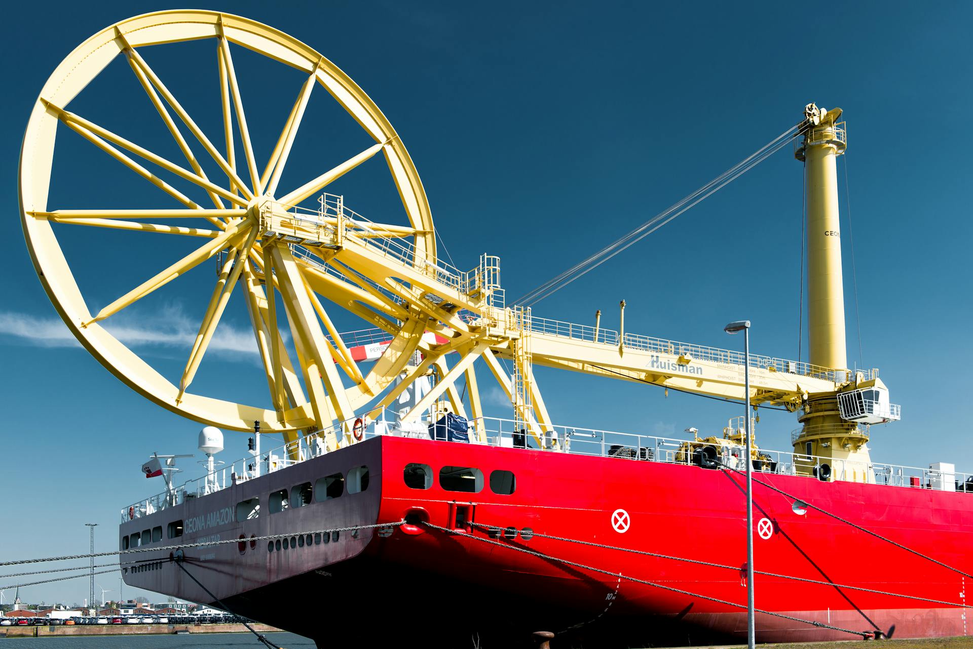A red industrial cargo ship docked in Bremerhaven Harbor under a clear blue sky.