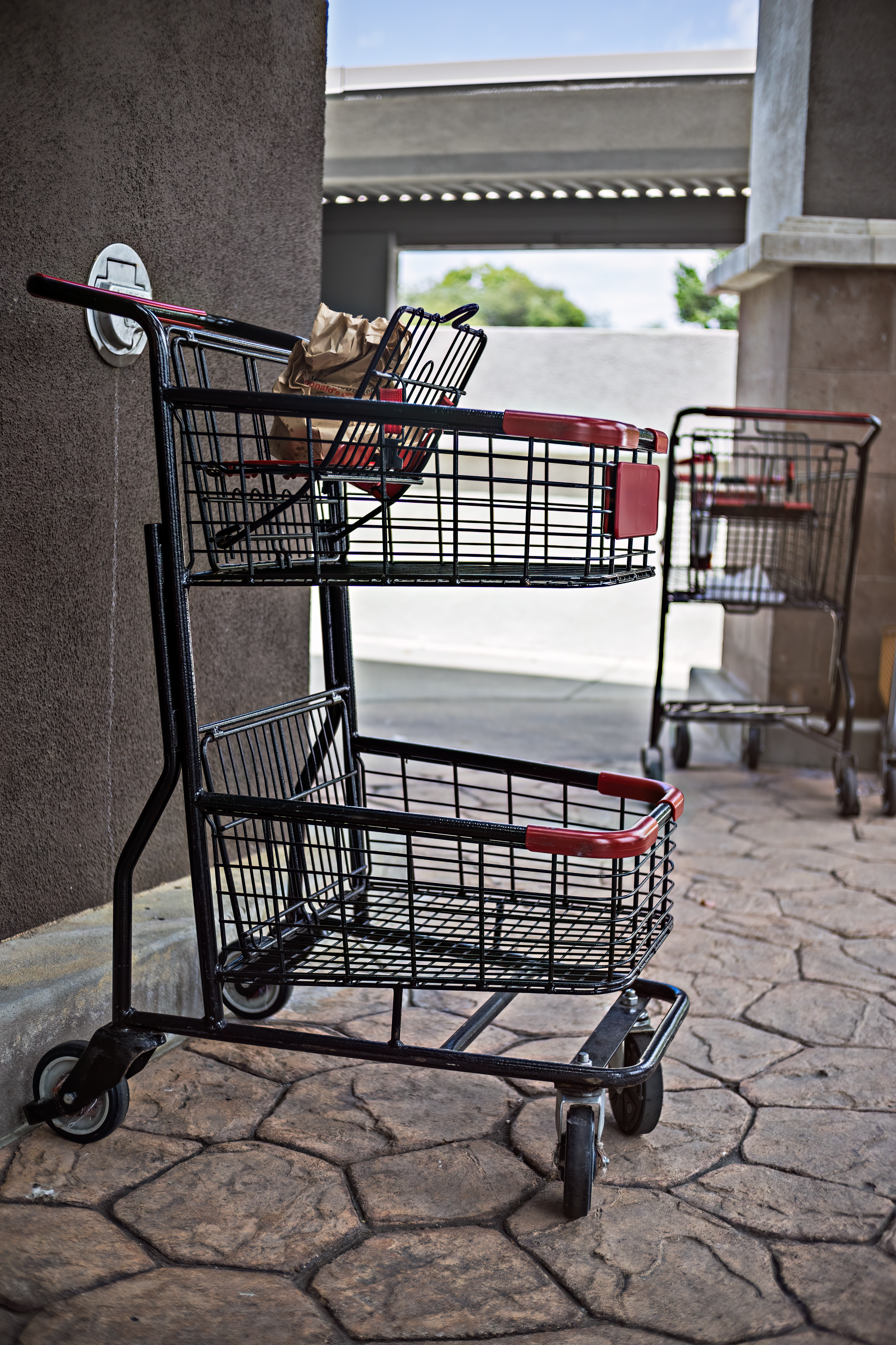 Empty shopping carts by a wall in a market setting, awaiting use.