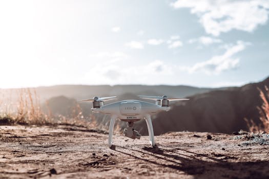 A white drone rests on a mountain terrain under a clear sky, ready for flight.