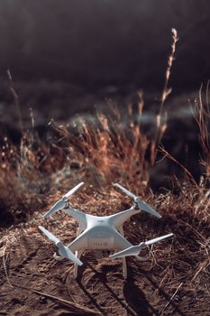A white drone with propellers rests on a grassy landscape under natural daylight.