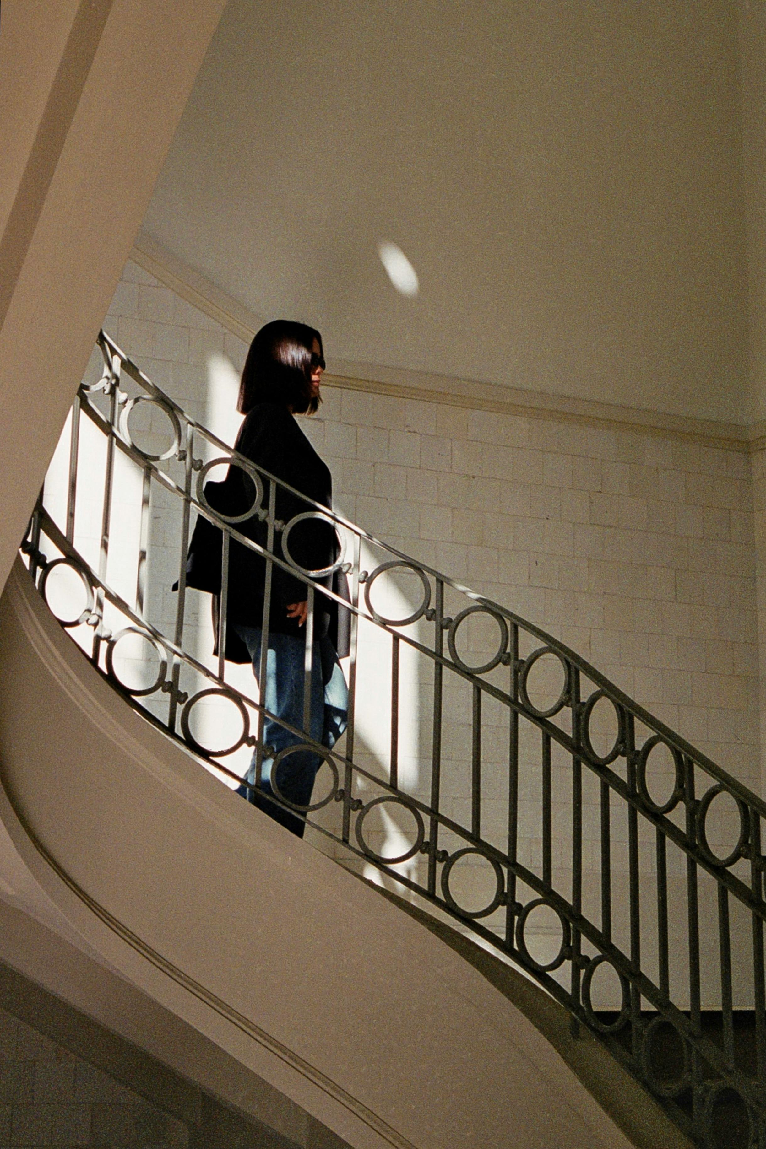 A fashionable woman ascends a sunlit staircase, capturing urban elegance in Porto, Portugal.