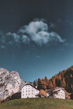 山上背景中，风景优美的乡村房屋映衬着晴朗的秋日天空