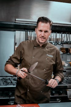 Chef sharpening a knife in a commercial kitchen, showcasing culinary expertise.