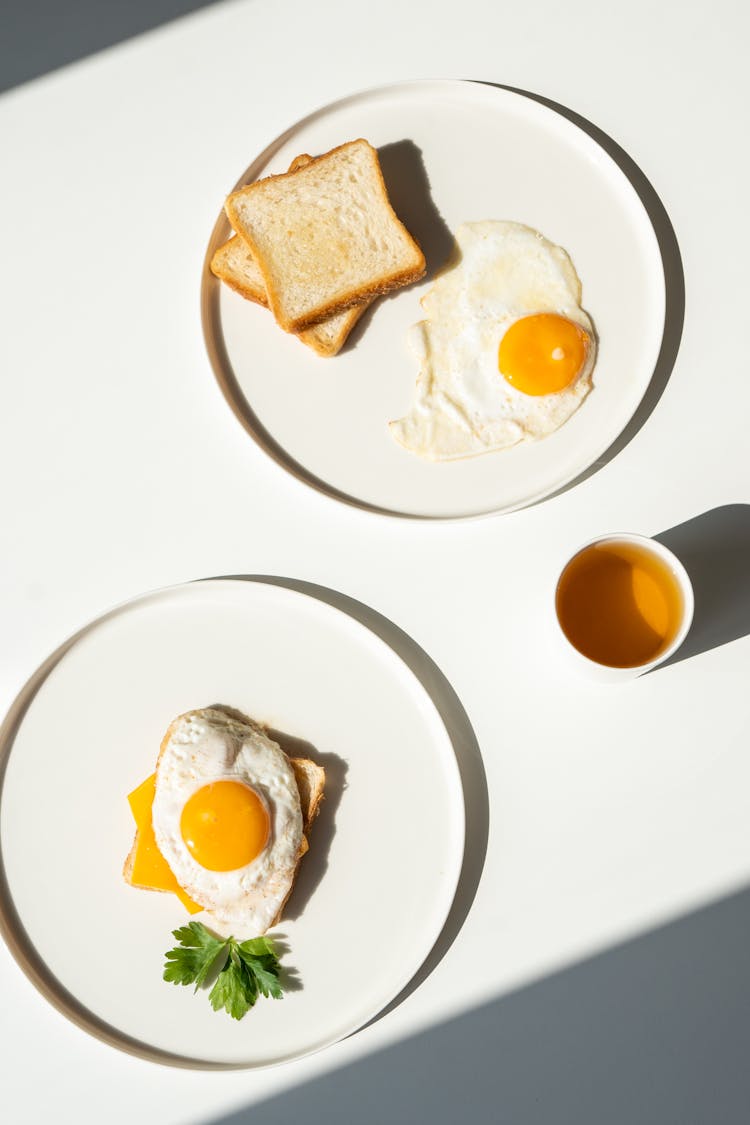 Fried Eggs And Toast On White Plates 