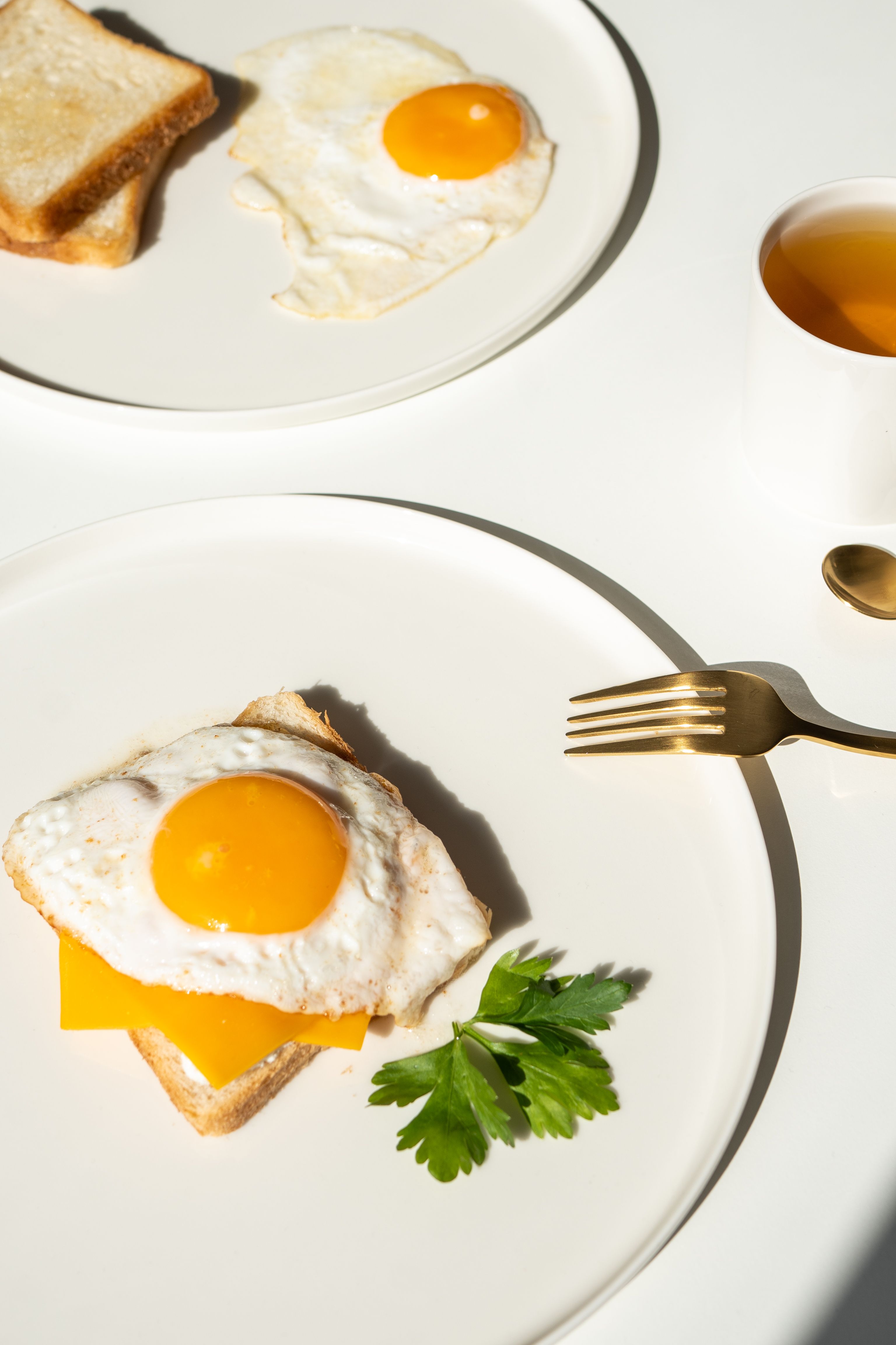 Fresh breakfast spread featuring sunny-side up eggs on toast with tea.