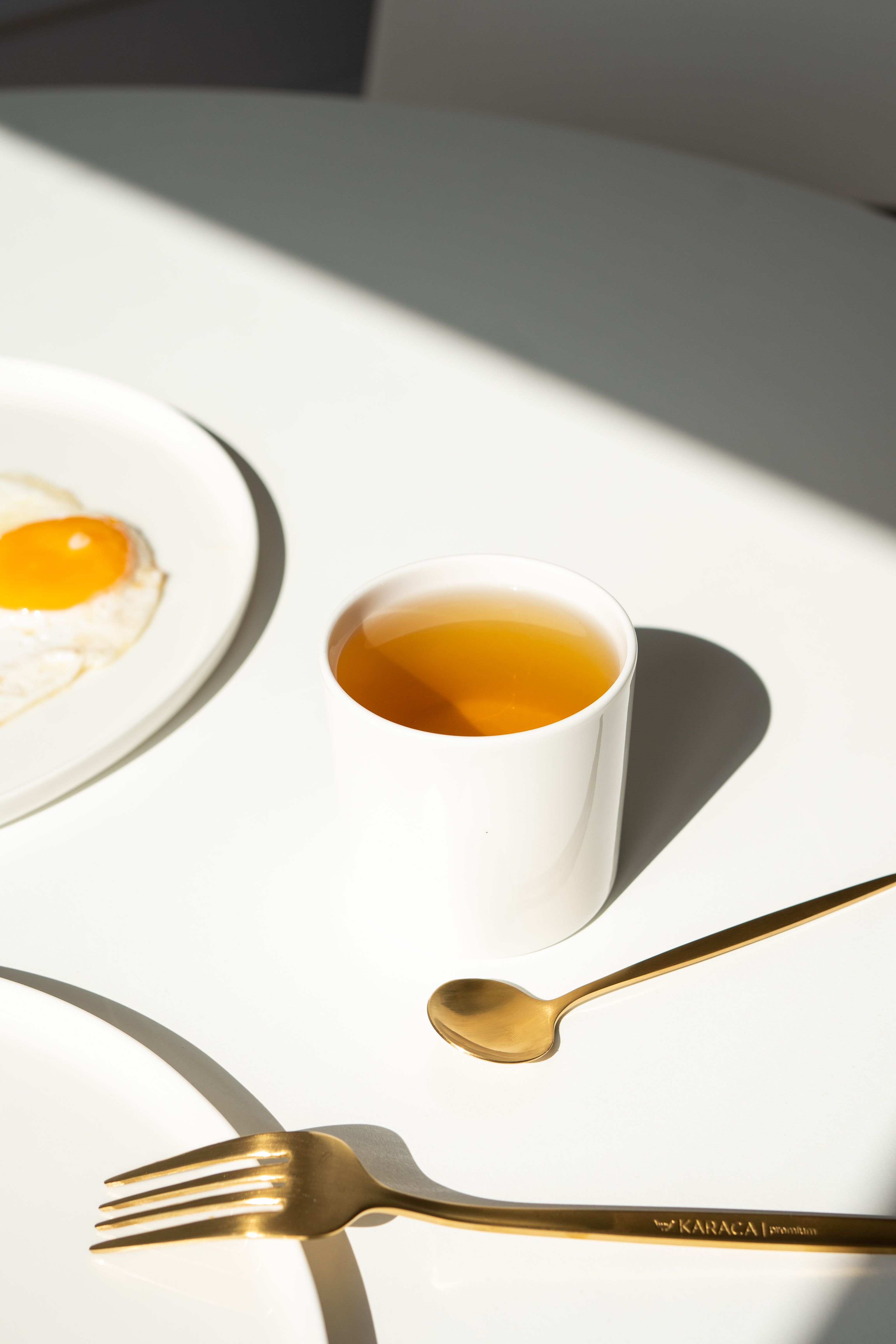 Elegant minimalist breakfast scene featuring a cup of tea and a sunny side up egg.