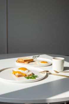 A bright and inviting breakfast scene featuring fried eggs, toast, and coffee on a white table.
