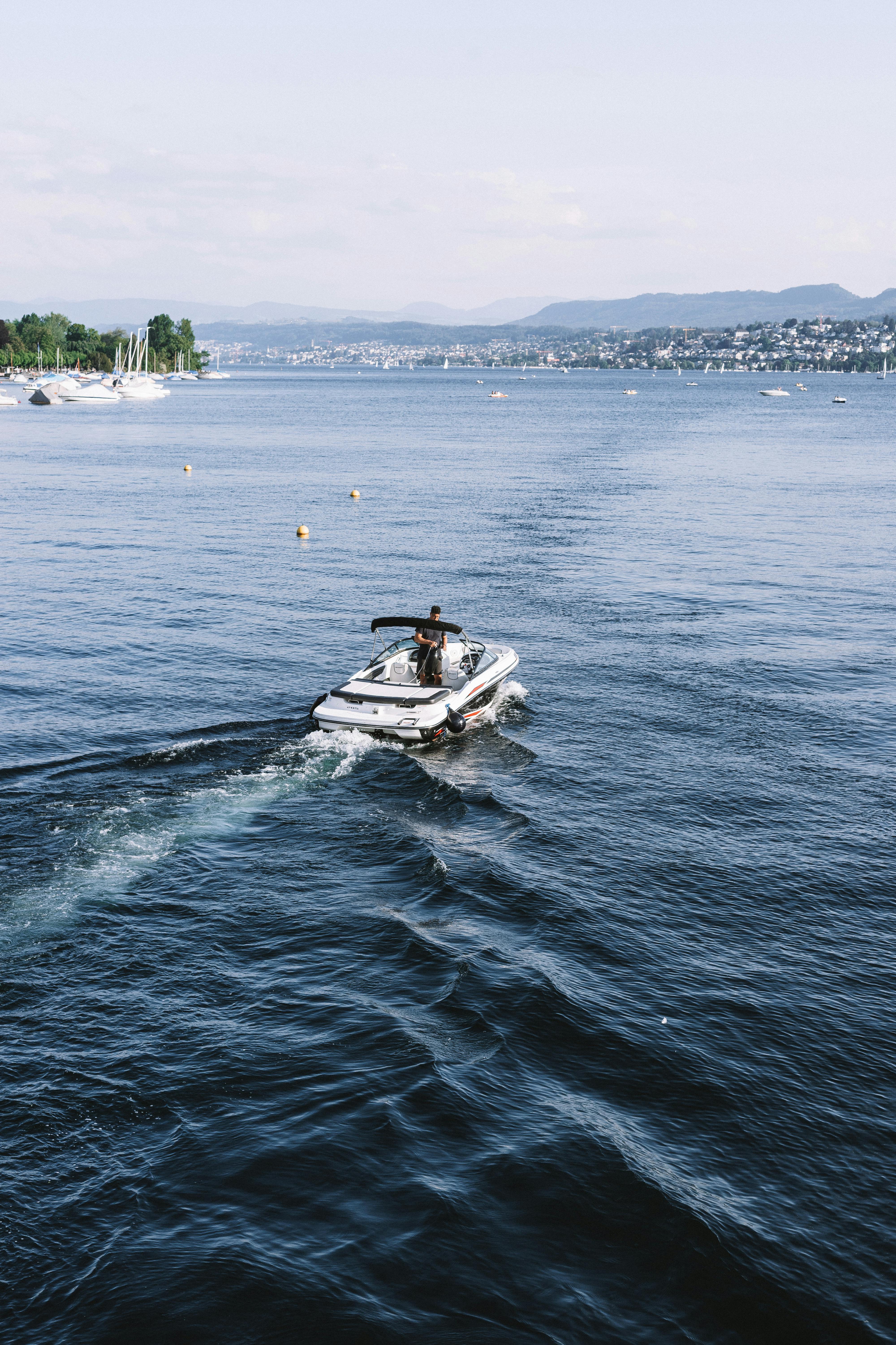 A motorboat gliding across a calm lake with distant shoreline views, ideal for travel imagery.