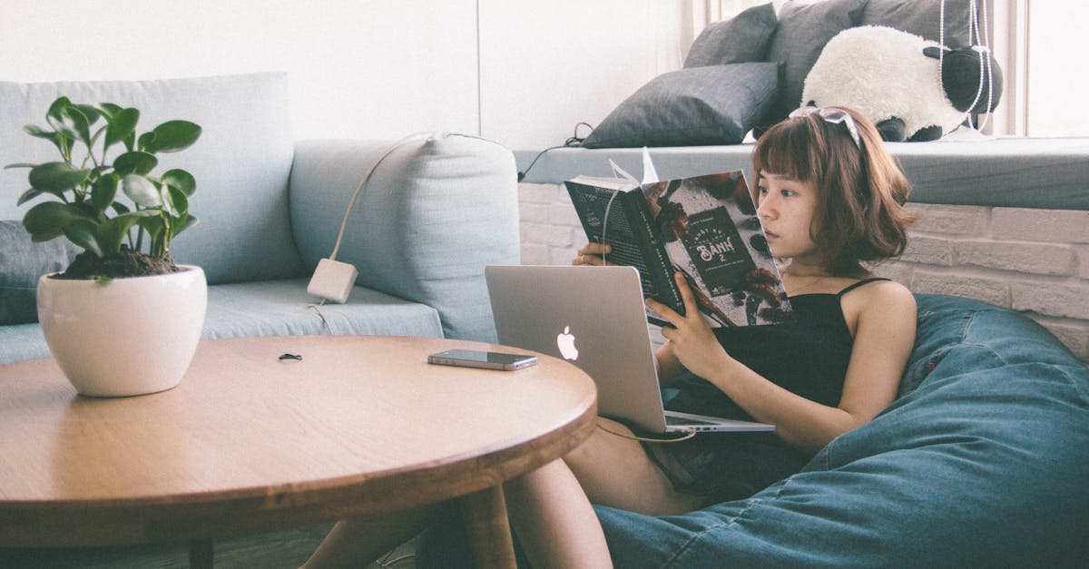 Woman Sitting on Bean Bag White Using Macbook in Front of Round Table With Green Leafed Plant