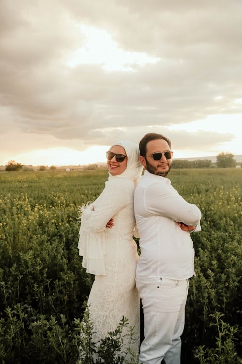 A man and woman in white standing in a field
