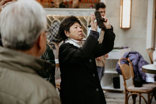Free Asian woman using smartphone to take photos in an indoor urban setting. Stock Photo
