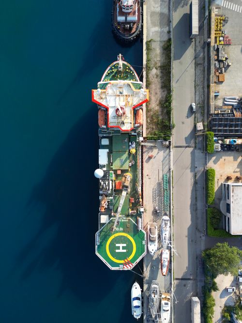 Free Aerial shot of a ship docked at Trieste harbor, featuring the helipad and surrounding boats. Stock Photo