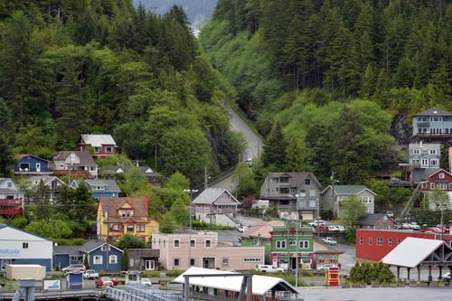 Free Picturesque small town surrounded by lush green hills and dense forest, showcasing colorful houses and serene scenery. Stock Photo