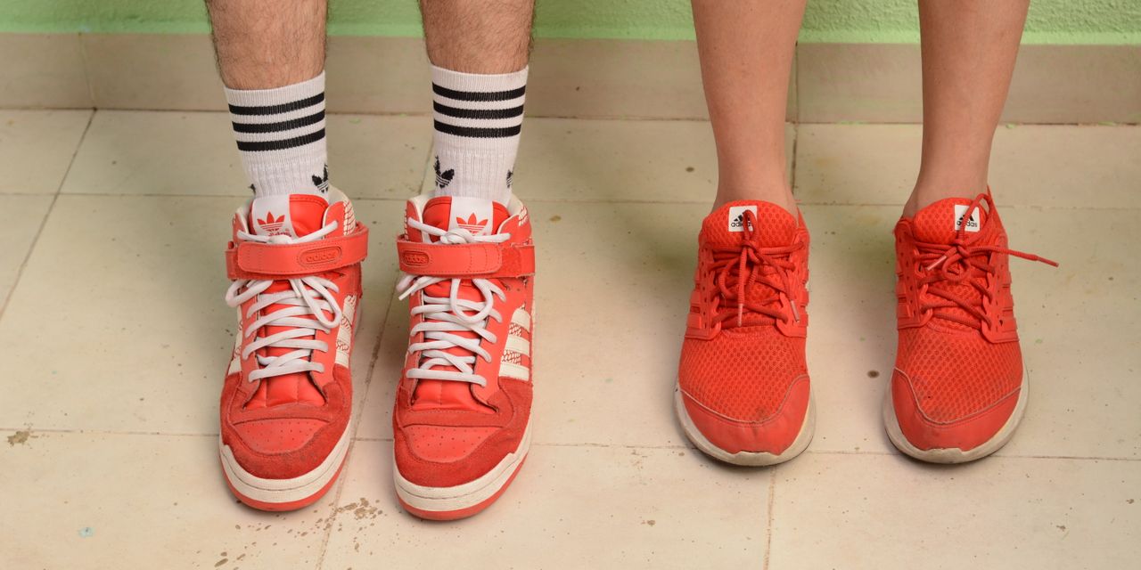 Two red sneakers with legs visible, showcasing fashion and style indoors.