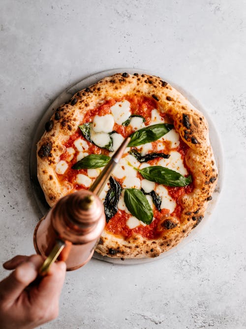 Taze Pişmiş Ekşi Mayalı Pizzanın üzerine Bakır Yağ Kutusundan Zeytinyağı Dökmek