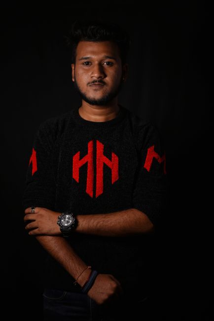 Studio portrait of a confident young man in a stylish sweater against a dark background.