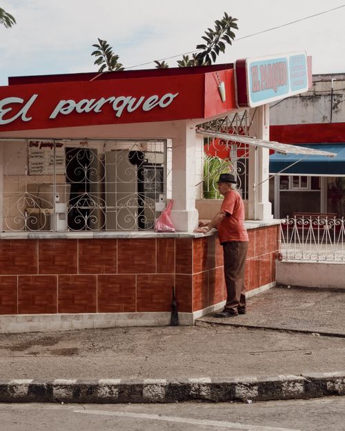 Free Elderly man standing by a colorful food bar on a city sidewalk. Stock Photo