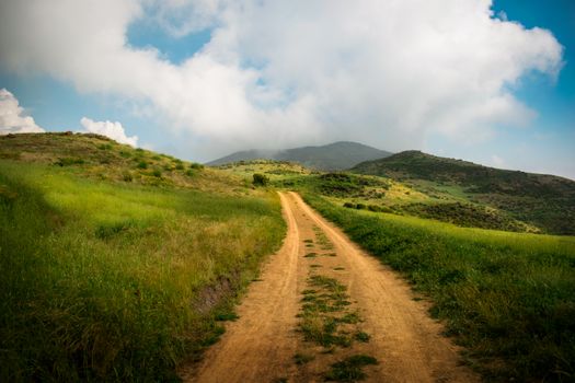 A picturesque dirt road winds through the green hills of Huamantanga, Lima, Peru.