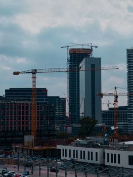Cityscape of Bratislava showcasing skyscraper construction with towering cranes against a cloudy sky.