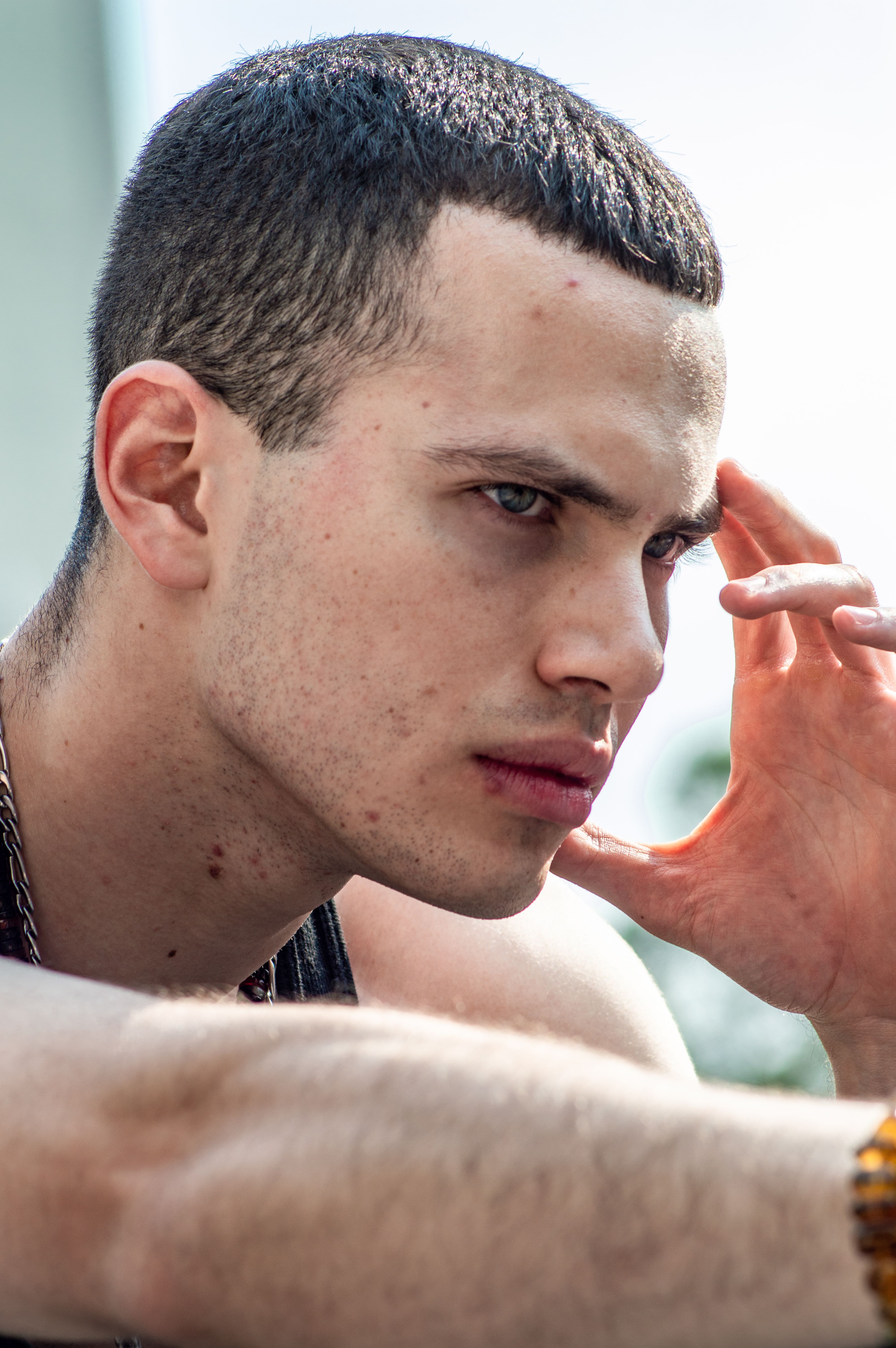 Close-up of a young man deep in thought outdoors on a sunny day.