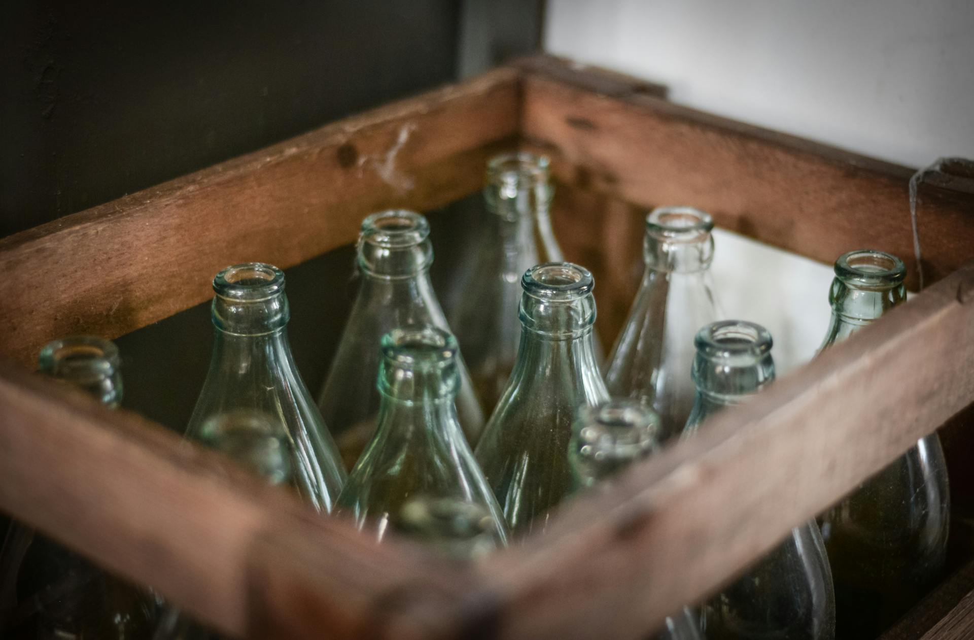 A close-up shot of a wooden crate filled with empty glass bottles, perfect for vintage themes.