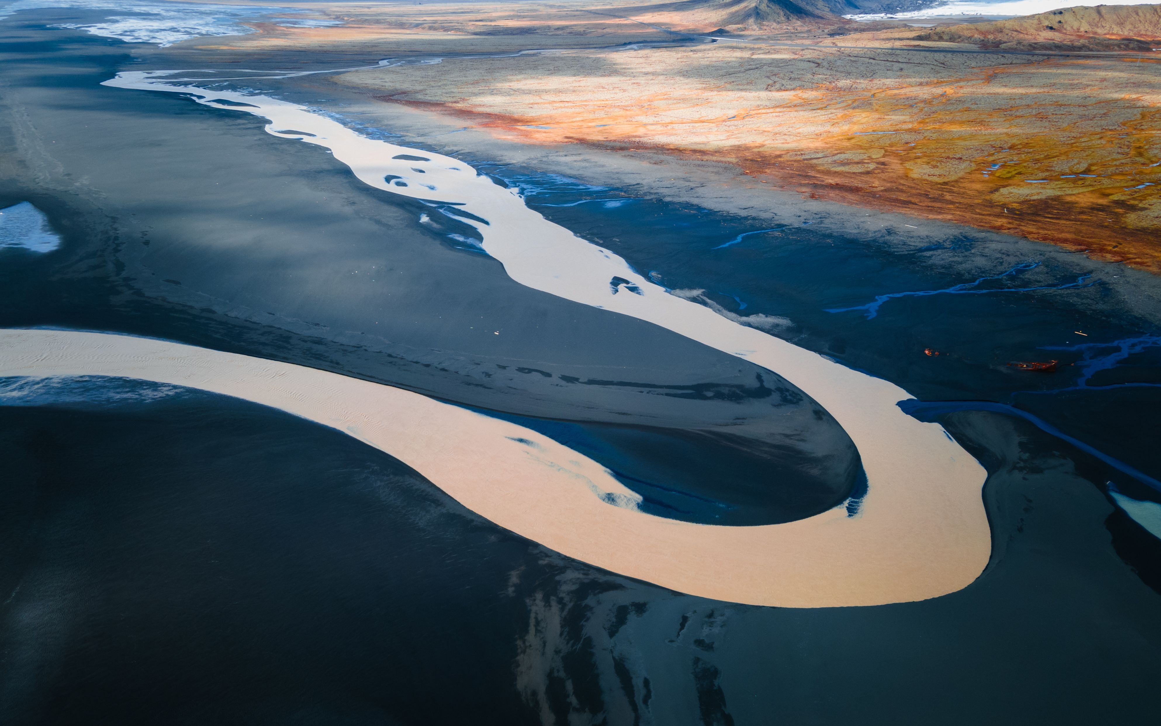 A breathtaking aerial view of a meandering river through a colorful and expansive landscape.