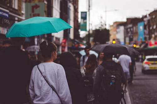 Crowd Under Umbrellas on the Sidewalk