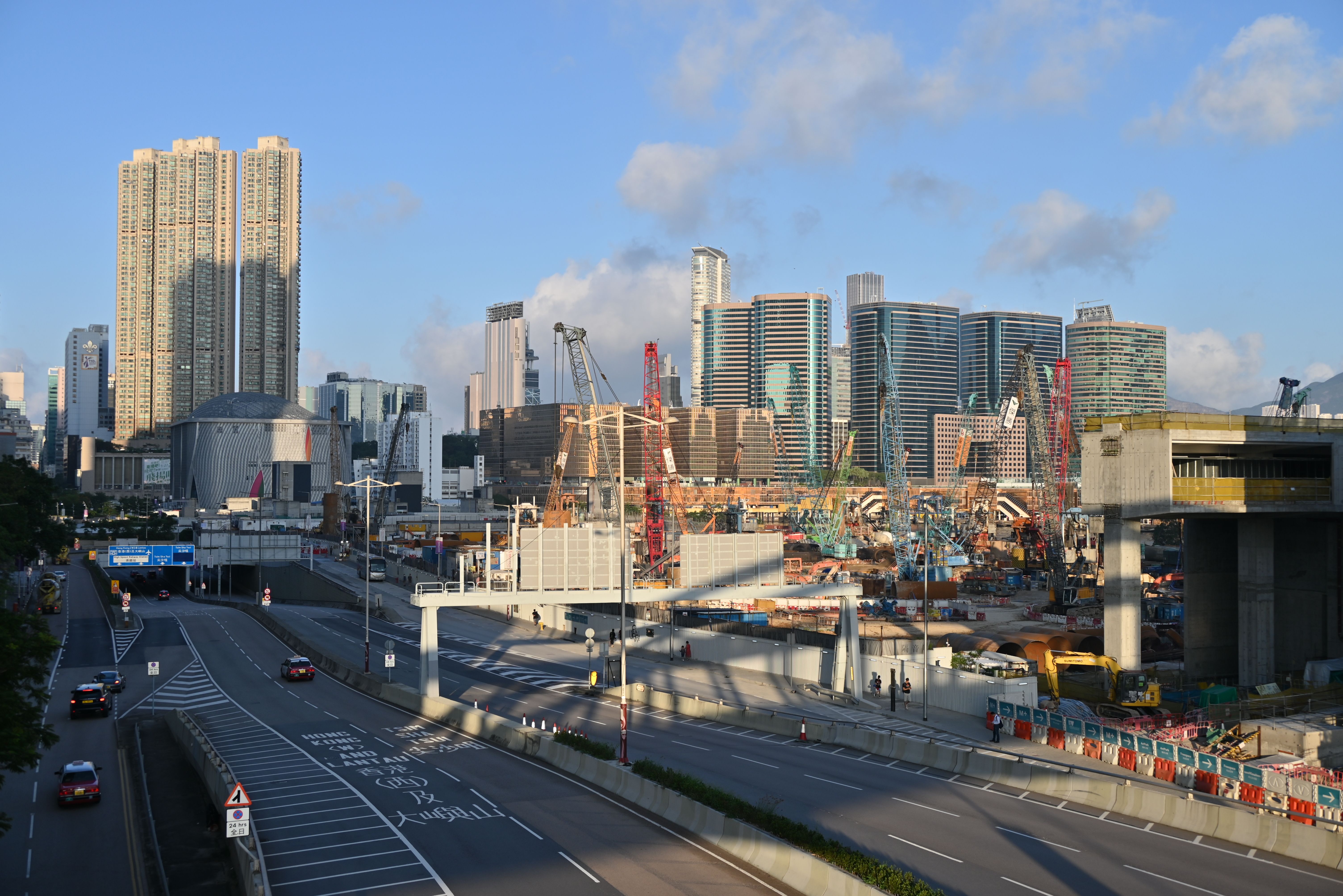 Skyscrapers and construction in West Kowloon, Hong Kong under a clear sky.