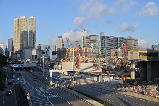 Skyscrapers and construction in West Kowloon, Hong Kong under a clear sky.