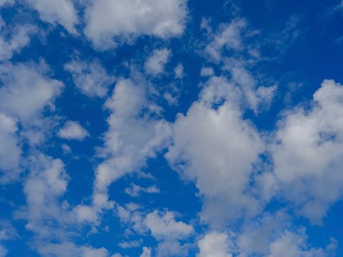 Free A vivid depiction of a clear blue sky filled with fluffy white clouds casting a serene atmosphere. Stock Photo