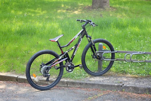 A mountain bike parked on a bike rack in a sunny urban park setting.