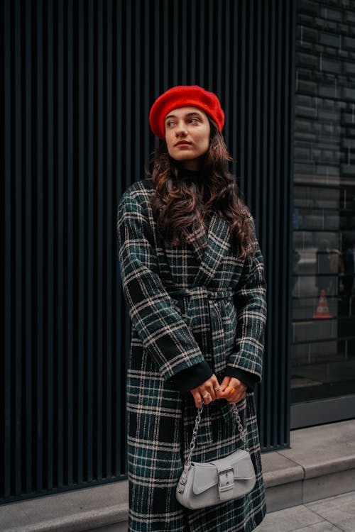 Young Brunette Wearing a Checkered Coat and Red Beret and Standing on a Sidewalk 