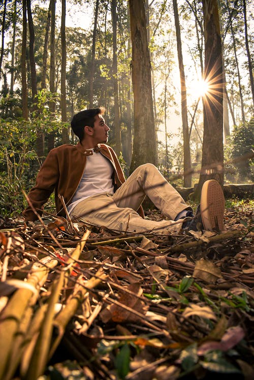 Man in Jacket Sitting in Forest and Posing