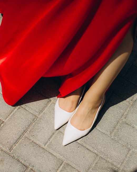 Stylish image of a woman's legs in white high heels and a red dress, perfect for fashion and elegance themes.
