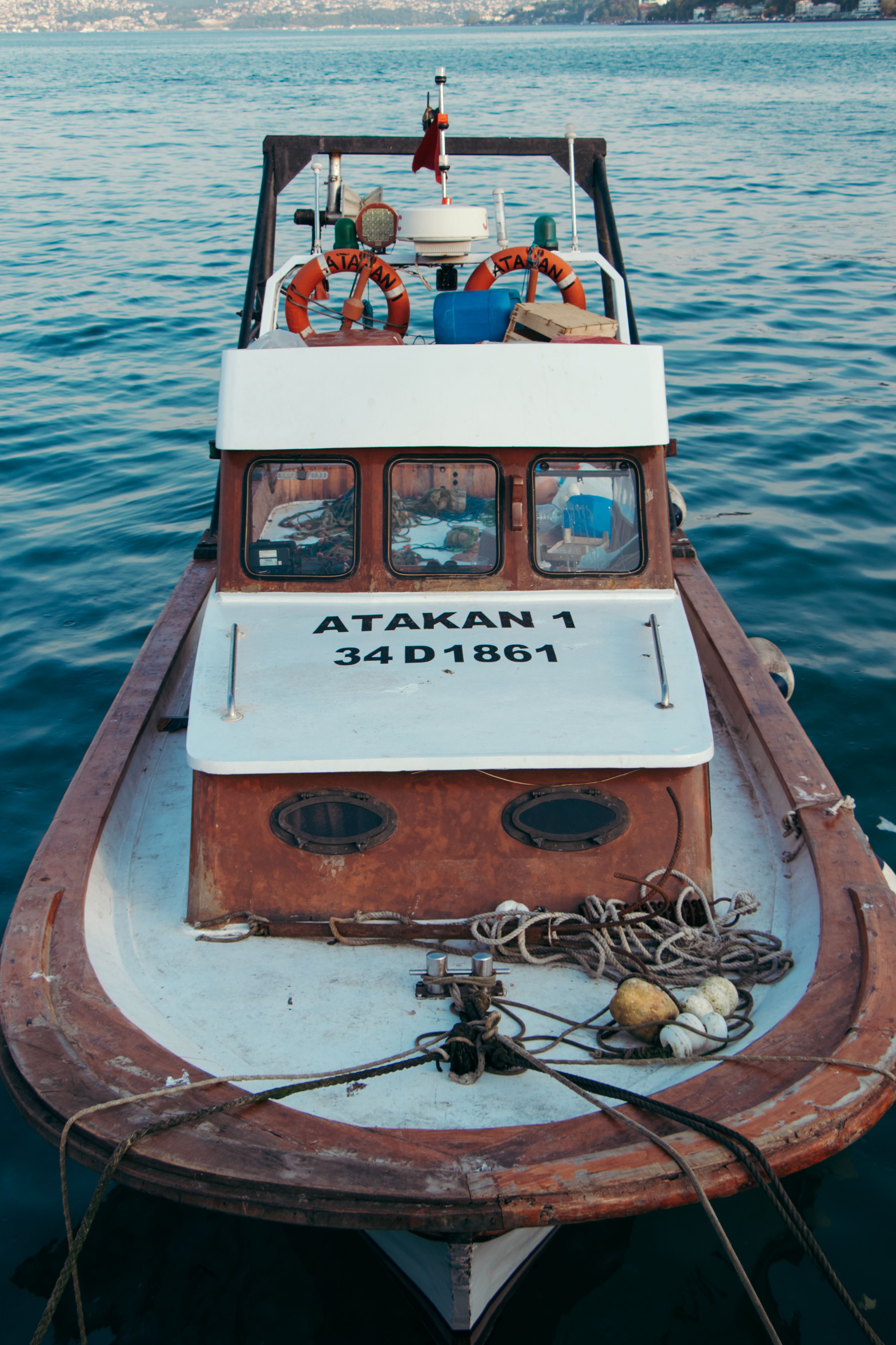 Rustic fishing boat 'Atakan 1' anchored on the calm blue sea, showcasing nautical elements.