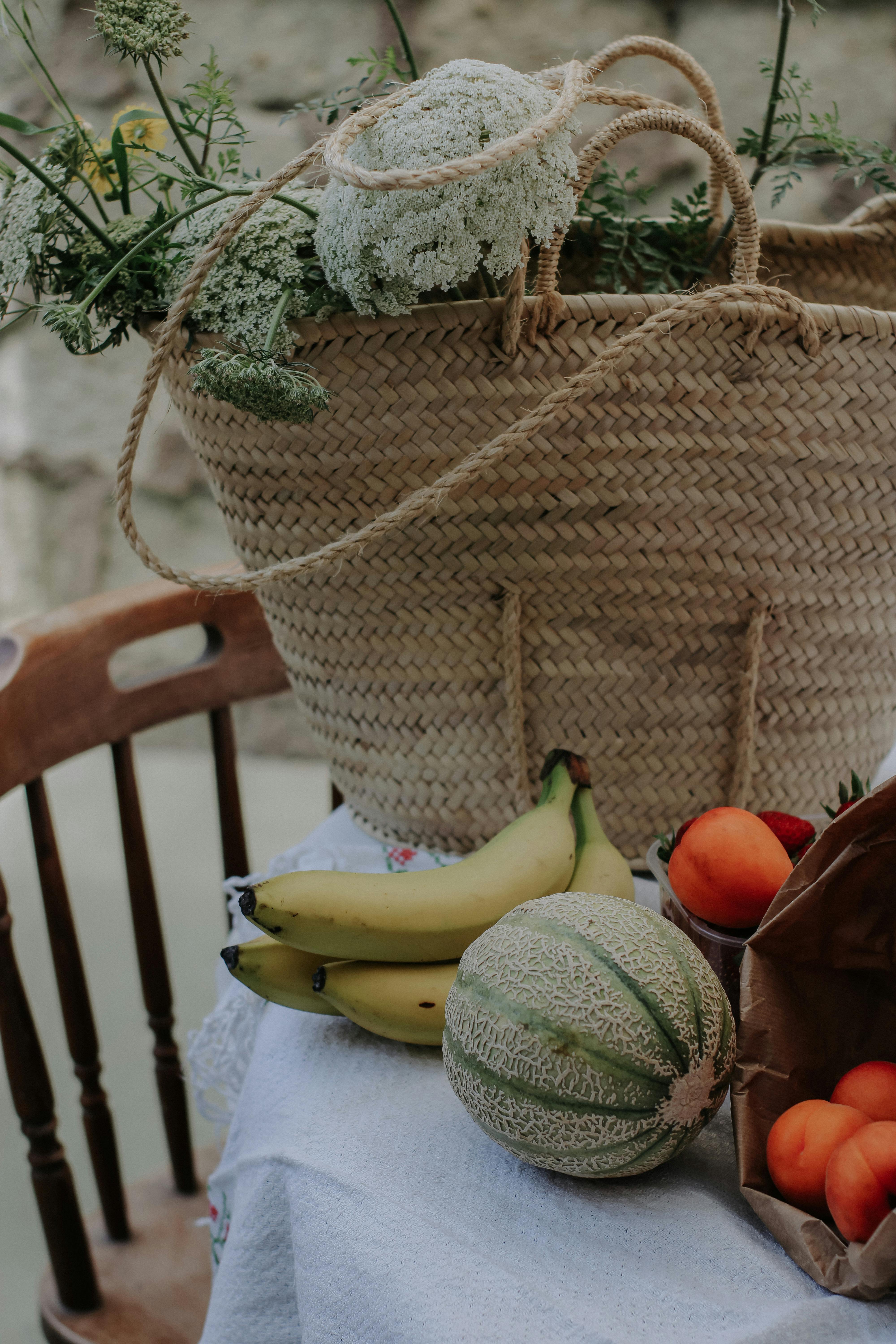 A natural still life composition featuring fruits, flowers, and a woven basket.