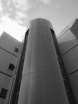 Black and white photo of a modern urban building captured from a low angle.