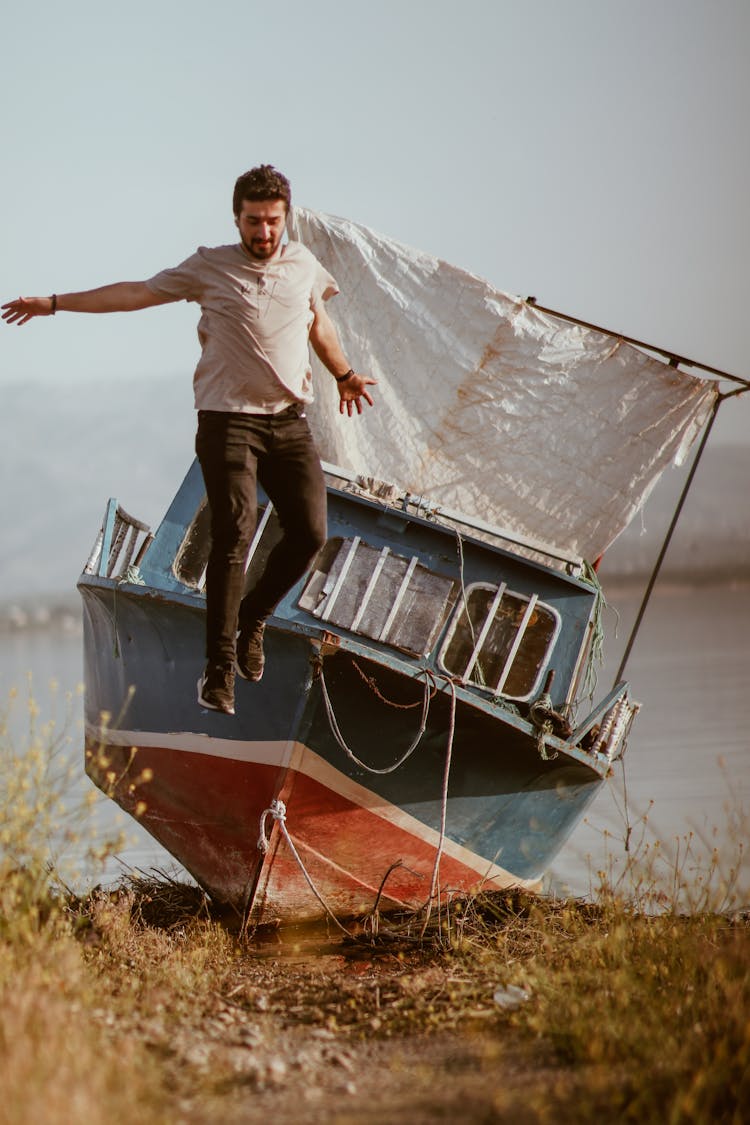 Man Jumping From Boat With Sail