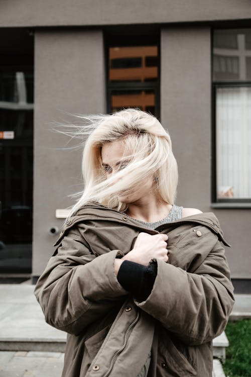 Foto Van Staande Vrouw, Gekleed In Bruine Jas Met Haar Haren Over Haar Gezicht