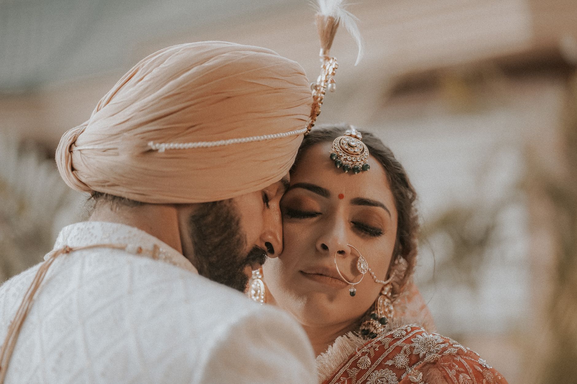 A newlywed couple sharing a tender moment in traditional Indian wedding attire, highlighting cultural elegance.