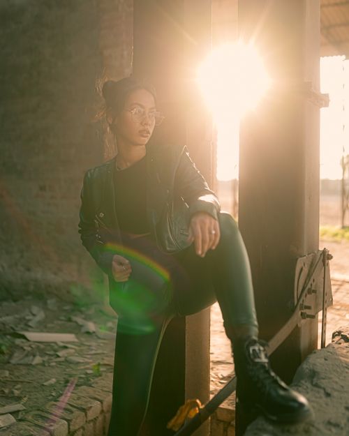 Free Stylish woman in black outfit posing outdoors against sunlight in urban setting. Stock Photo