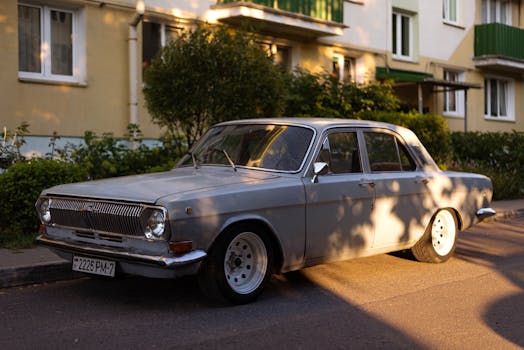 A classic Gaz-24 car parked on an urban street, bathed in warm sunlight.