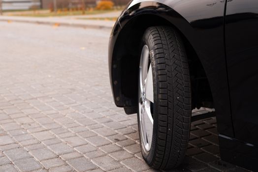 A black car's tire on a cobblestone road captures the essence of urban transportation.