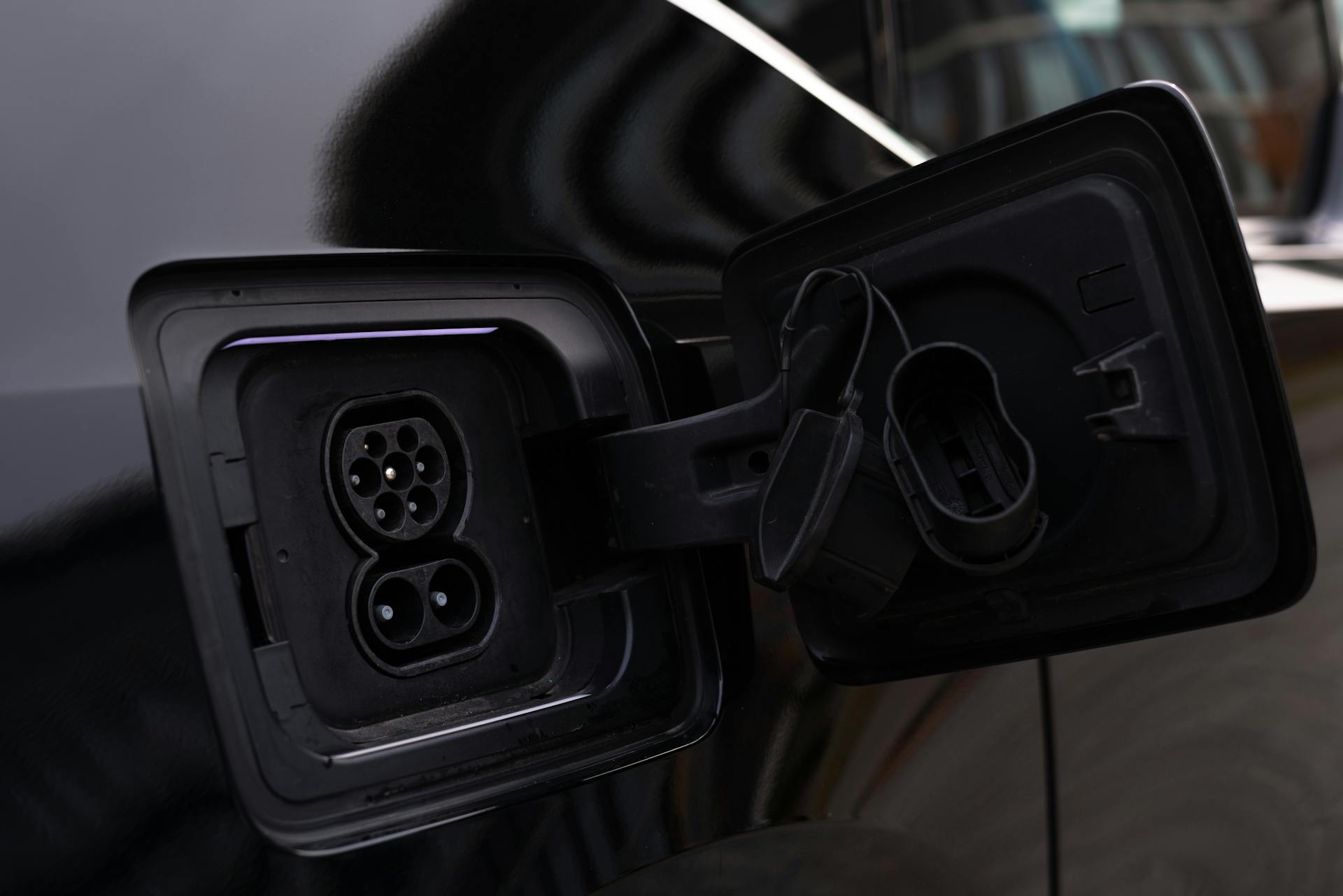 Close-up image of an electric vehicle charging port on a black car.