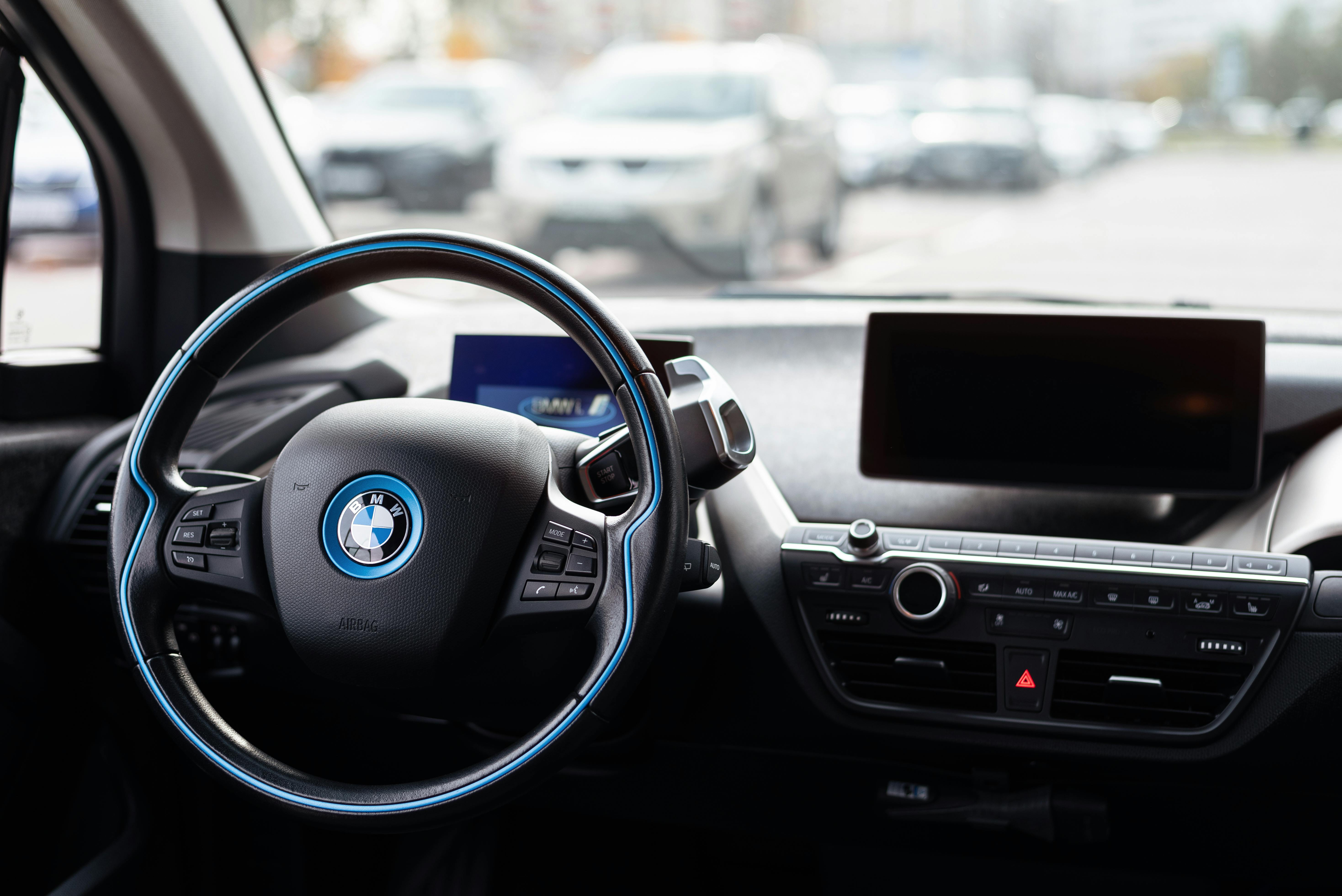 Free Interior of a modern car showcasing sleek dashboard and steering wheel in an urban setting. Stock Photo