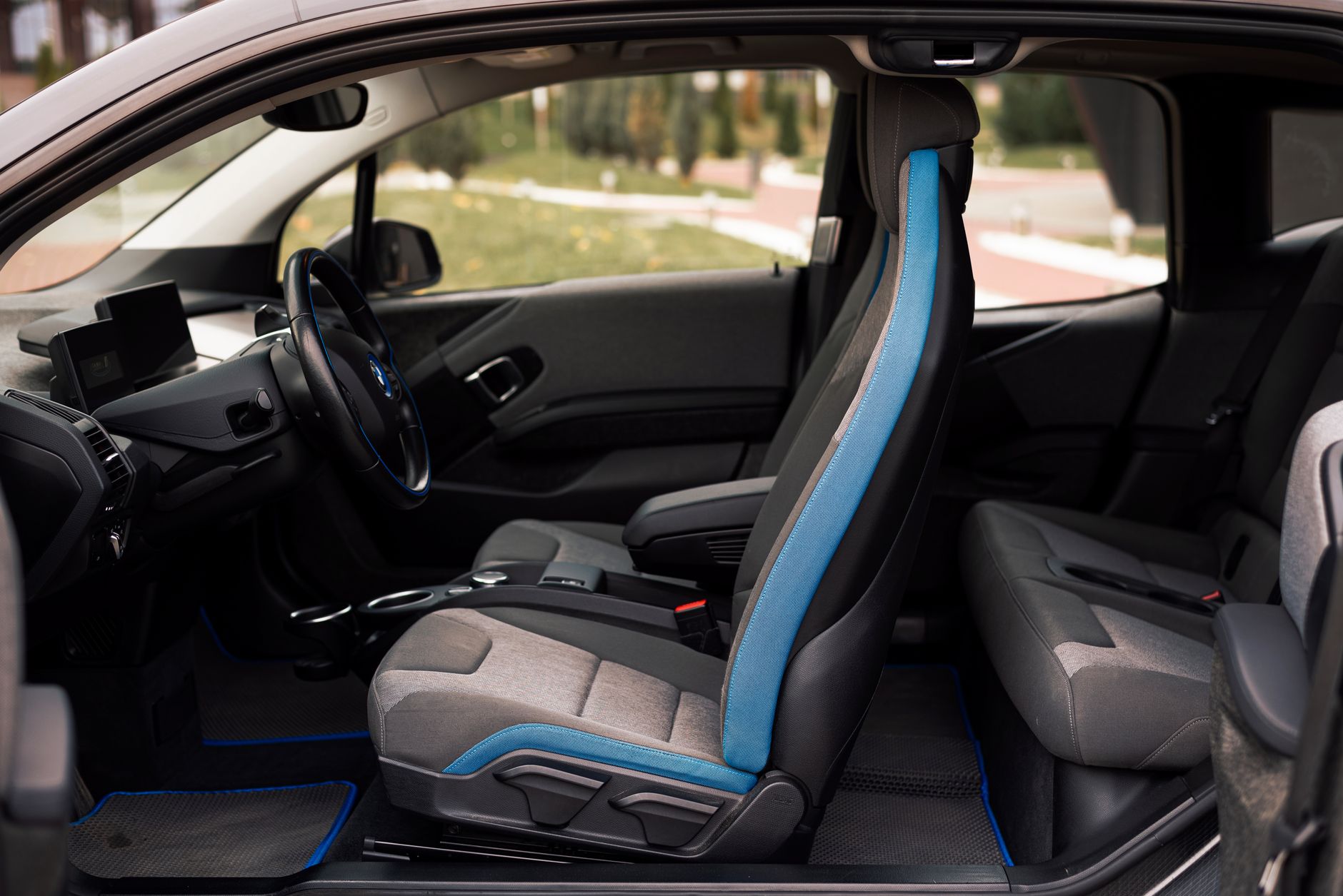 A sleek interior of a modern car showcasing the front and rear seats and steering wheel details.
