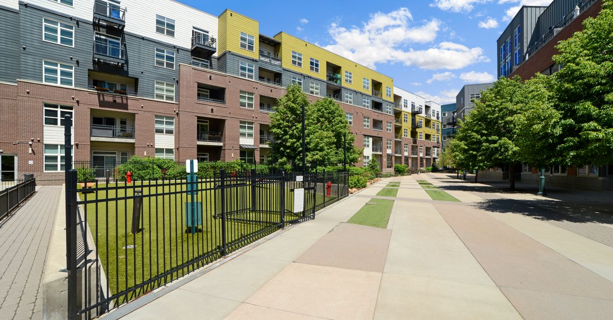 Colorful modern residential buildings with green courtyard and clear blue sky.