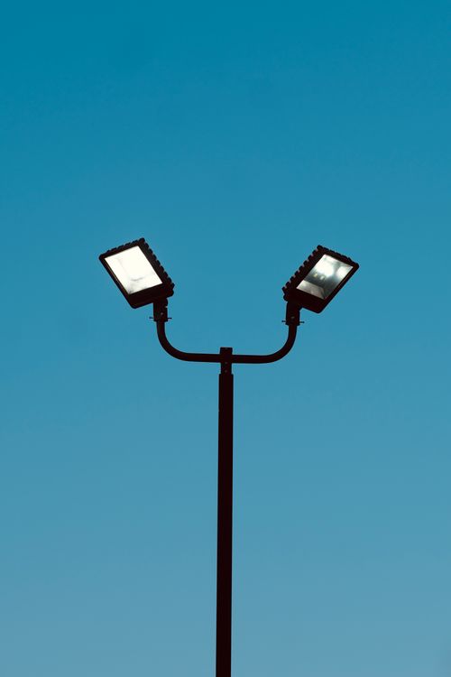 Free A minimalist shot of a dual-head street lamp silhouetted against a clear blue sky. Stock Photo
