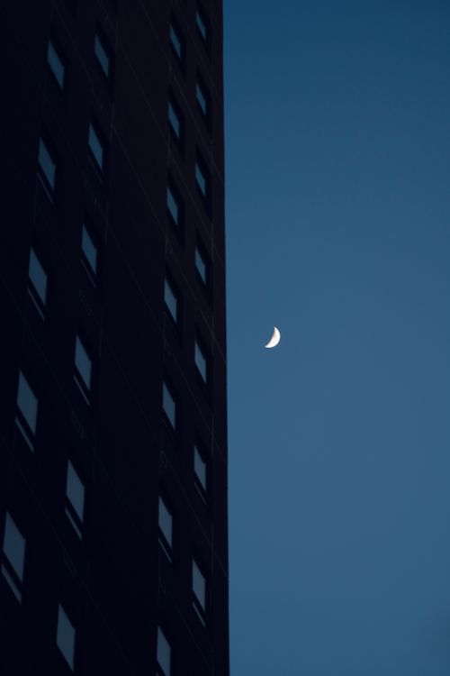 Free A striking view of the crescent moon beside an apartment building at dusk in Waterloo, Ontario. Stock Photo
